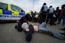 A pro-Palestine campaigner lies on the road during a protest outside the Thales factory in Govan (Andrew Milligan/PA)