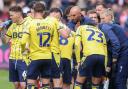 Oxford United players take on drinks and instructions during a break in play